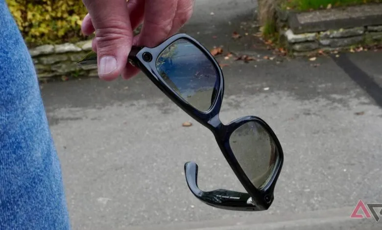 Hand holding Ray-Ban Meta smart glasses with black frames and tinted lenses.