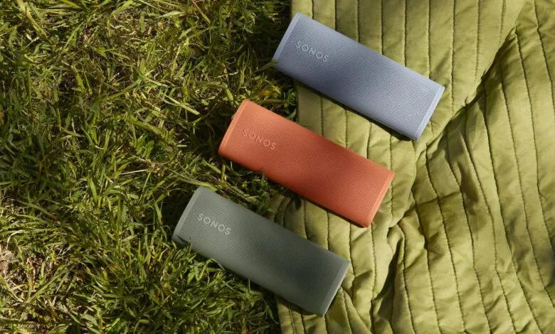 Three colorful Sonos Roam speakers on a green blanket and grass.