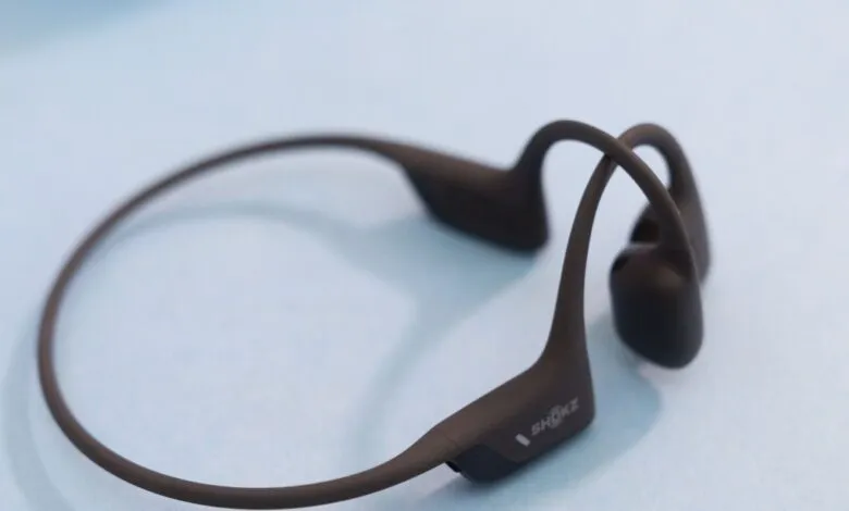Shokz OpenRun Pro bone conduction headphones on light blue surface.