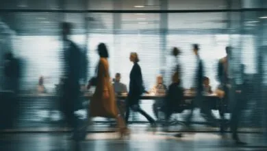 Blurred view of business people walking past a conference room.