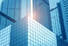 Modern glass skyscrapers with blue tint and sunlight reflecting off windows.