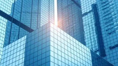 Modern glass skyscrapers with blue tint and sunlight reflecting off windows.