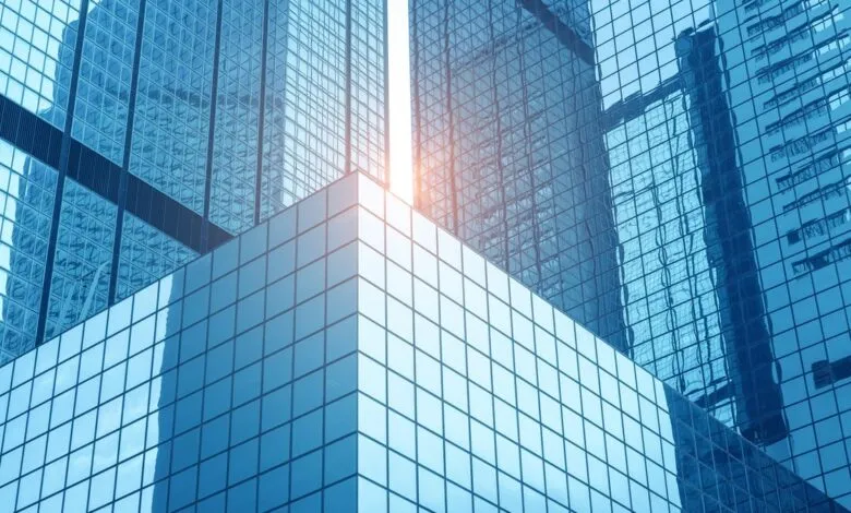 Modern glass skyscrapers with blue tint and sunlight reflecting off windows.