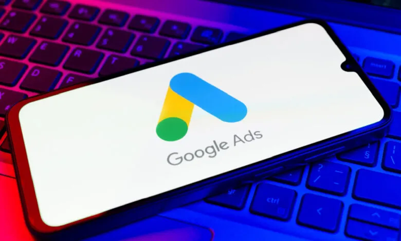 Smartphone displaying Google Ads logo on a laptop keyboard.