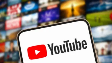 YouTube logo displayed on a smartphone screen with video thumbnails blurred in the background.