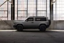 Gray SUV parked in a warehouse with large windows.
