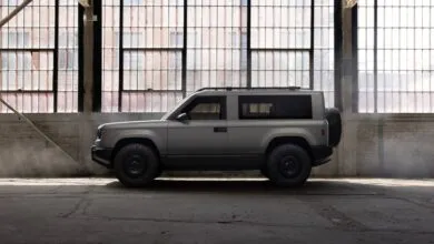 Gray SUV parked in a warehouse with large windows.