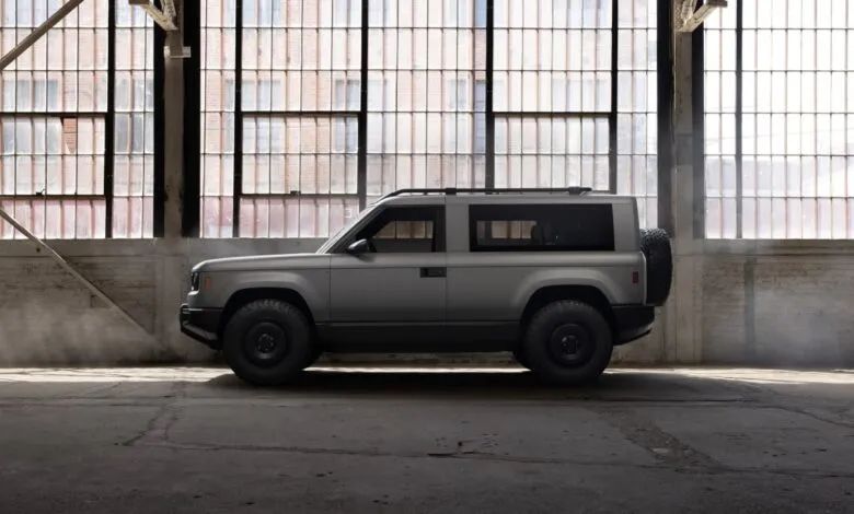 Gray SUV parked in a warehouse with large windows.