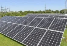 Array of solar panels in a field under a blue sky.