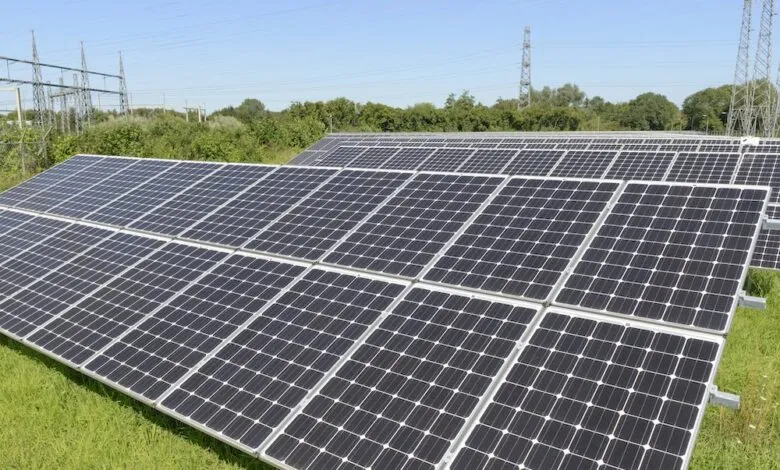 Array of solar panels in a field under a blue sky.