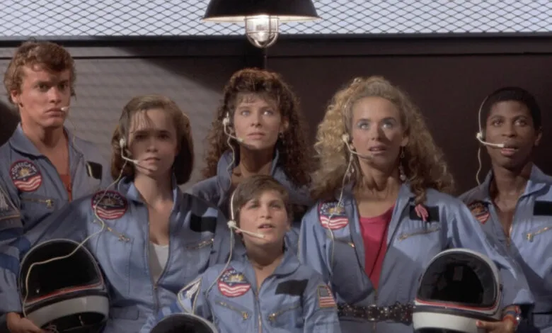 Group of young actors in SpaceCamp movie wearing flight suits and headsets.