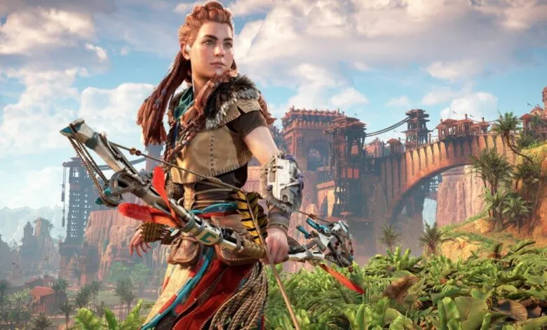 Aloy from Horizon Forbidden West stands ready with her bow in a lush, vibrant landscape.