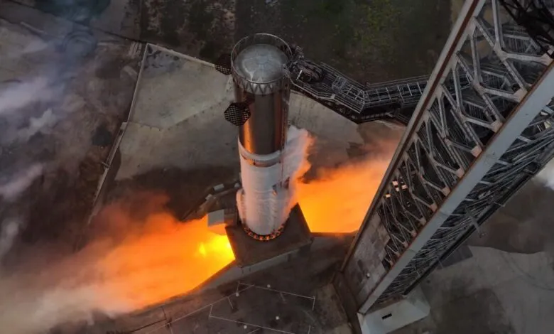 SpaceX Starship test firing with flames and steam visible.