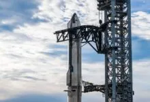 SpaceX Starship rocket stacked on launch tower with blue sky and clouds.