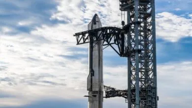 SpaceX Starship rocket stacked on launch tower with blue sky and clouds.