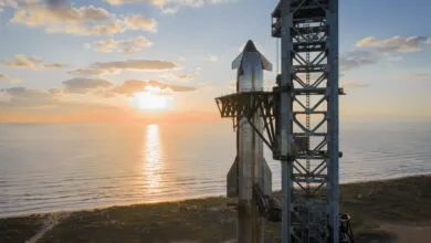 SpaceX Starship on launchpad at sunrise, ocean backdrop.