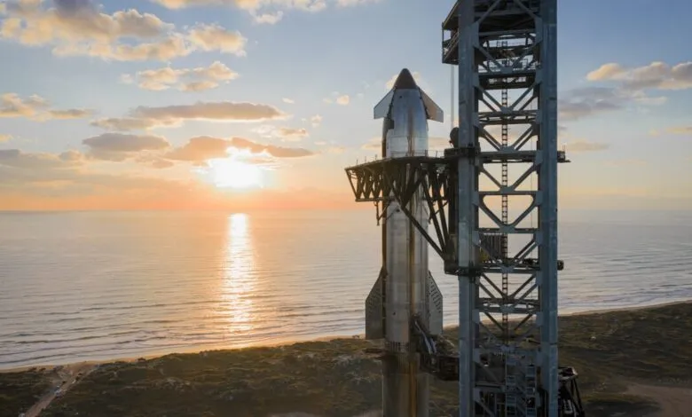 SpaceX Starship on launchpad at sunrise, ocean backdrop.