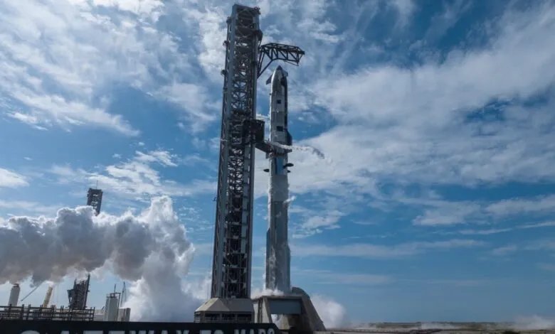 SpaceX Starship rocket on launchpad with vapor trails against blue sky.