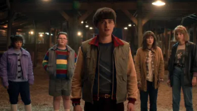 Group of 'Stranger Things' characters stand in a barn, looking concerned.