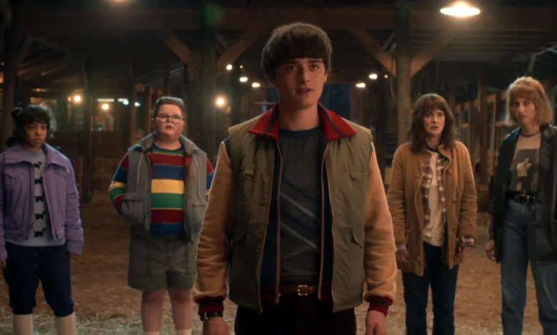 Group of 'Stranger Things' characters stand in a barn, looking concerned.