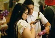 Couple at wedding playing with phones and a pink Tamagotchi toy.