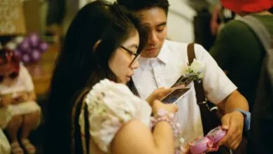 Couple at wedding playing with phones and a pink Tamagotchi toy.