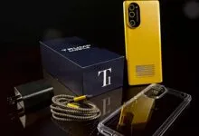 Trump Mobile phone with box, charger, cable, and case on a reflective surface.