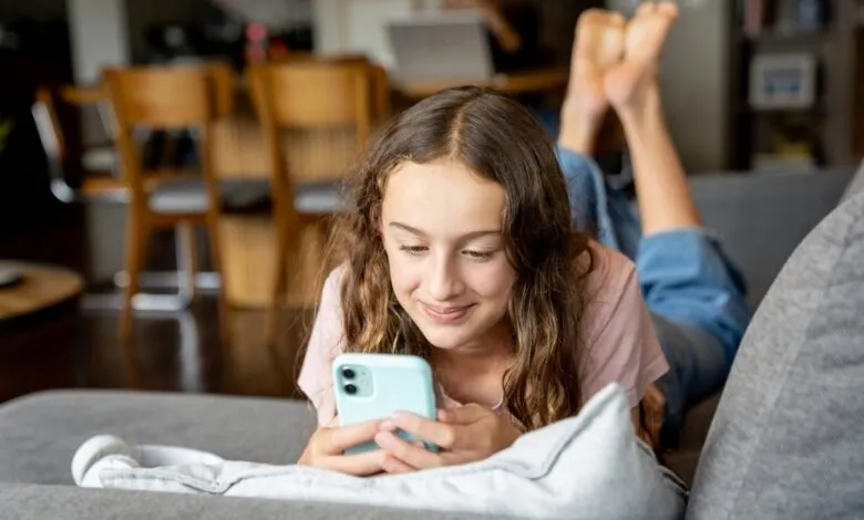 Girl lying on couch using smartphone, smiling and relaxed.