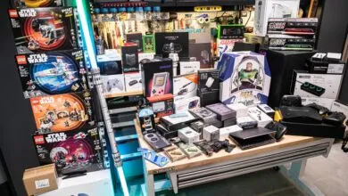 Table filled with electronics, toys, and gadgets, including Star Wars Lego sets and a Buzz Lightyear figure.