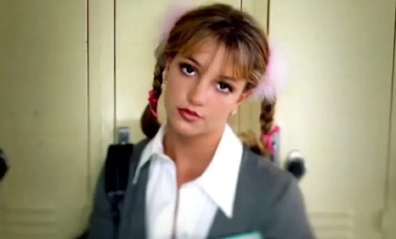Britney Spears in schoolgirl outfit with pigtails and pink hair ties.