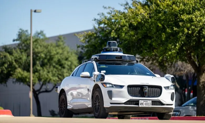 White Waymo Jaguar I-Pace self-driving car on a sunny street.