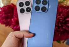 Hand holding pink and blue Xiaomi 14 Pro smartphones with Leica camera.