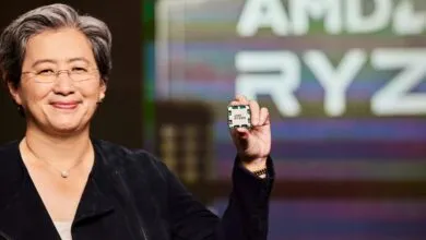 Lisa Su holds up an AMD Ryzen processor, smiling confidently.