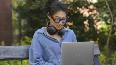 Woman with headphones using Dell XPS 13 laptop outdoors.