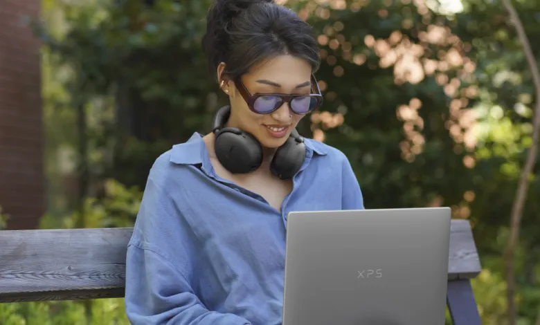 Woman with headphones using Dell XPS 13 laptop outdoors.