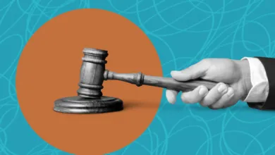 Hand holding gavel against orange circle and blue background.