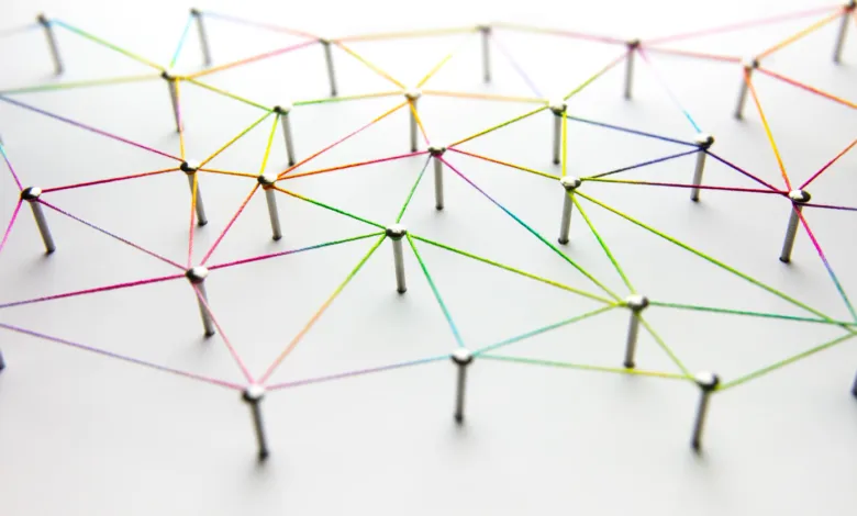 Network of colorful strings connecting pins on a white surface.