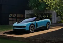 Light blue Ferrari sports car parked outside modern home.