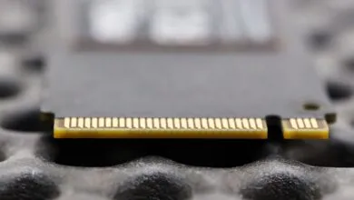 Close-up of a gray SSD card with gold connectors on a textured surface.