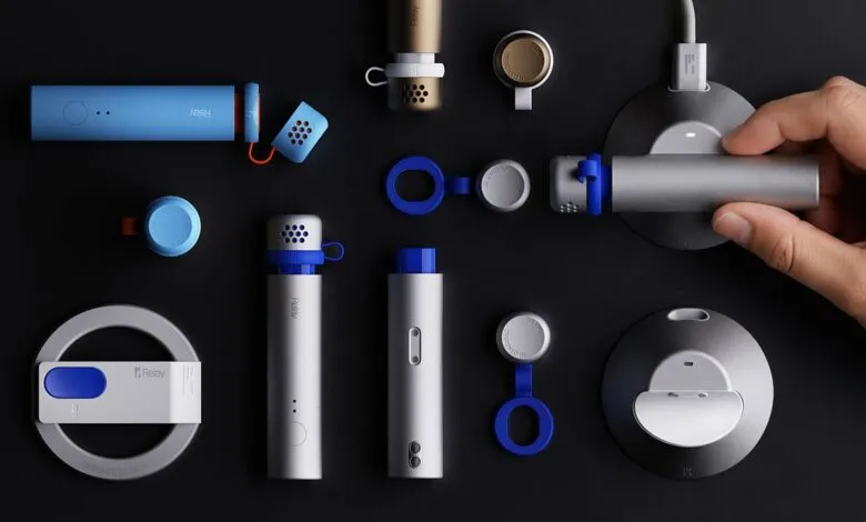 A hand places a sleek silver and blue Relay device onto a round charging dock against a dark background