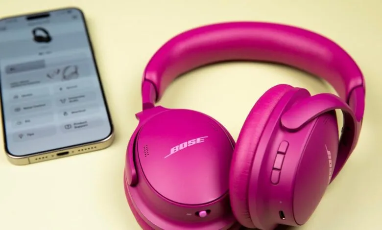 Vibrant pink Bose QuietComfort Headphones next to a smartphone displaying a companion app.