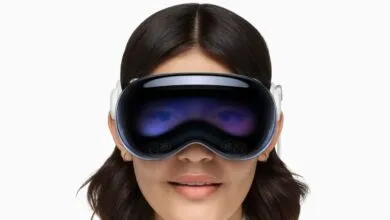 Close-up of a smiling person wearing the Apple Vision Pro headset against a white background.