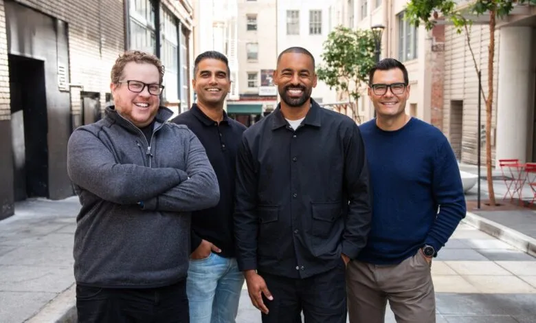 Four diverse business professionals smiling together outdoors in an urban courtyard