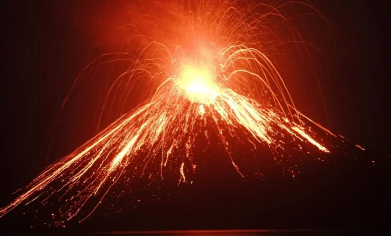 Anak Krakatau volcano erupts at night, spewing bright orange lava and glowing arcs of molten rock.