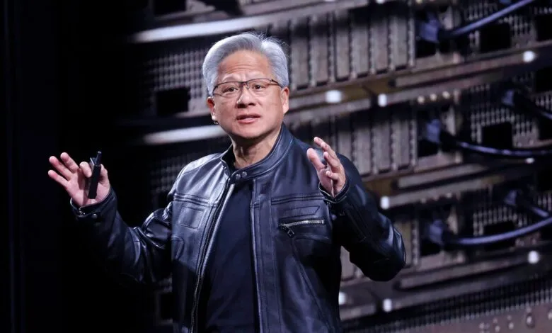 NVIDIA CEO Jensen Huang speaks on stage wearing his signature black leather jacket in front of server racks.