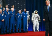 US President Donald Trump walking past a group of NASA astronauts in blue flight suits.