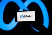 A smartphone displaying the Meta logo against a glowing blue infinity symbol background