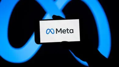 A smartphone displaying the Meta logo against a glowing blue infinity symbol background