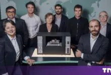 Group portrait of the Pasqal leadership team posing around a quantum computer model.