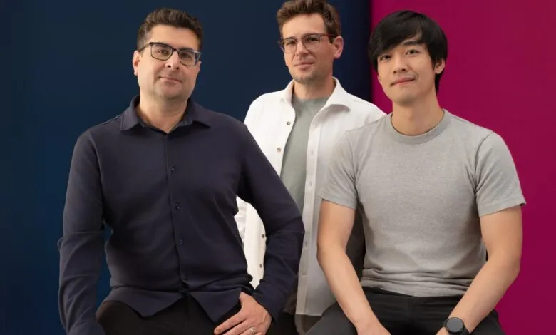 Three business leaders pose together against a blue and pink backdrop.